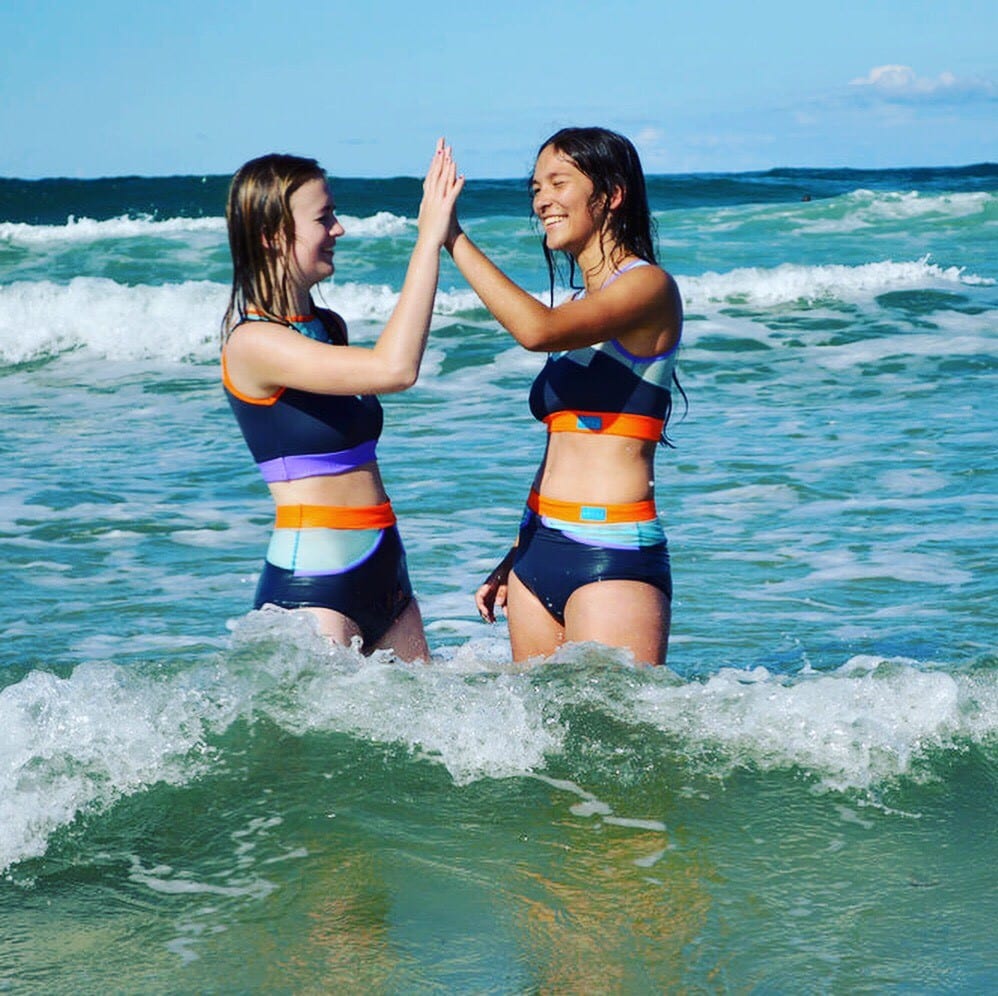 Two girls in the sea wearing sustainable swimwear