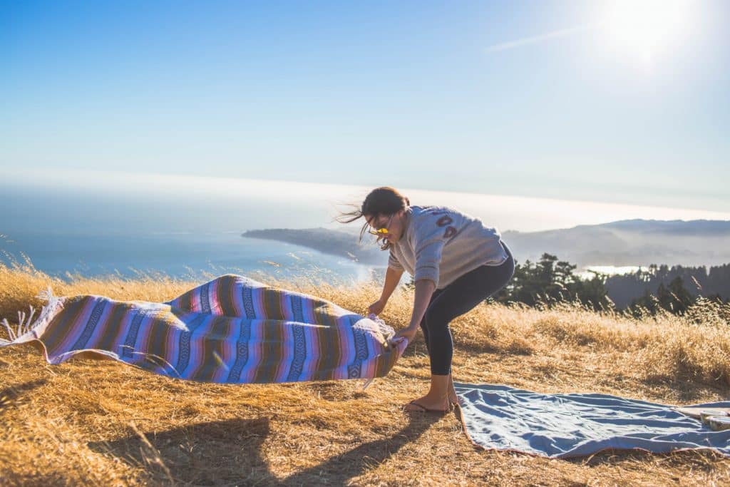 Woman laying down a blanket on the coast