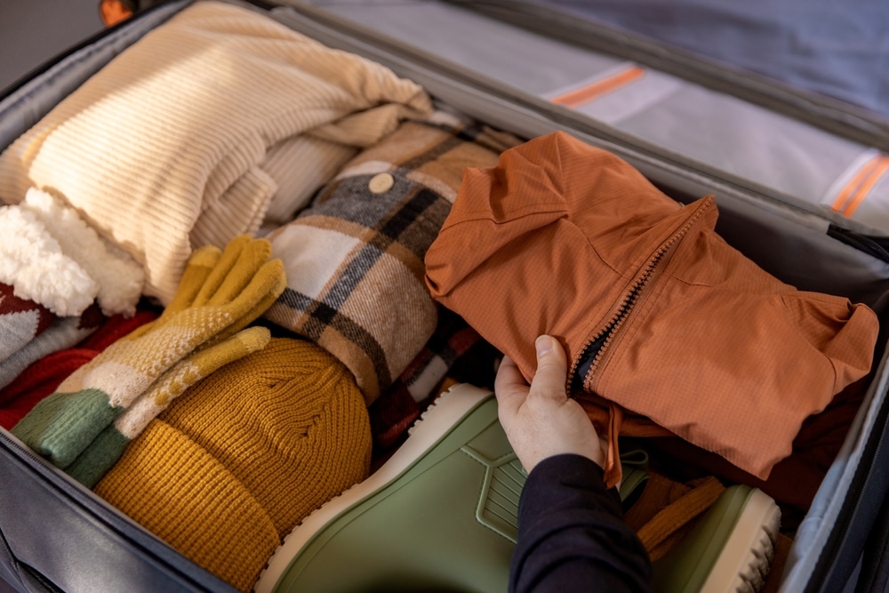 A woman packing clothes into an open suitcase