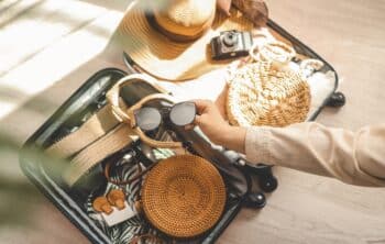 Woman packing sunglasses, hat, bag and other things.