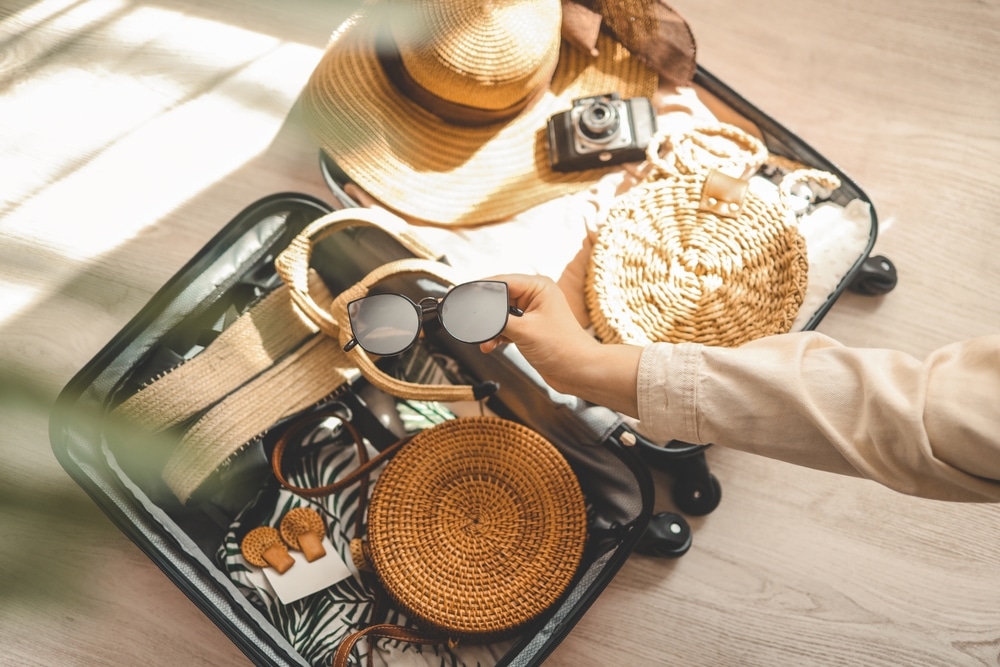 Woman packing sunglasses, hat, bag and other things.  